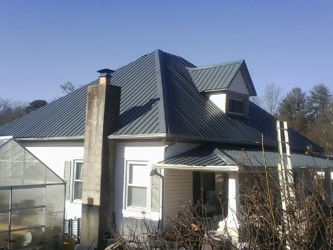 Dark blue standing seam metal roof on a white farmhouse with dormer — Slate & Tile Roof Repair by Roofing Brothers in East Liverpool