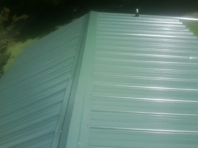 New green metal panels meeting at the ridge of a roof — Flat Roof Repair work by our crew in East Liverpool