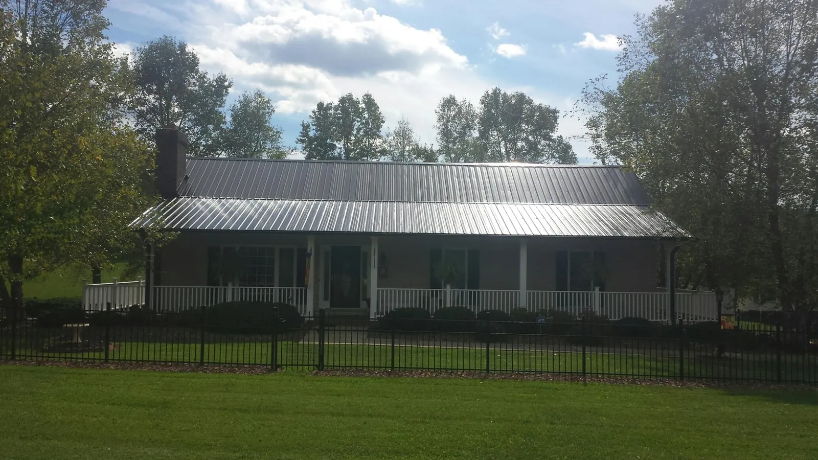 Gray metal roof on a brick ranch with a full width front porch — Gutter Guard Installation work by our crew in East Liverpool