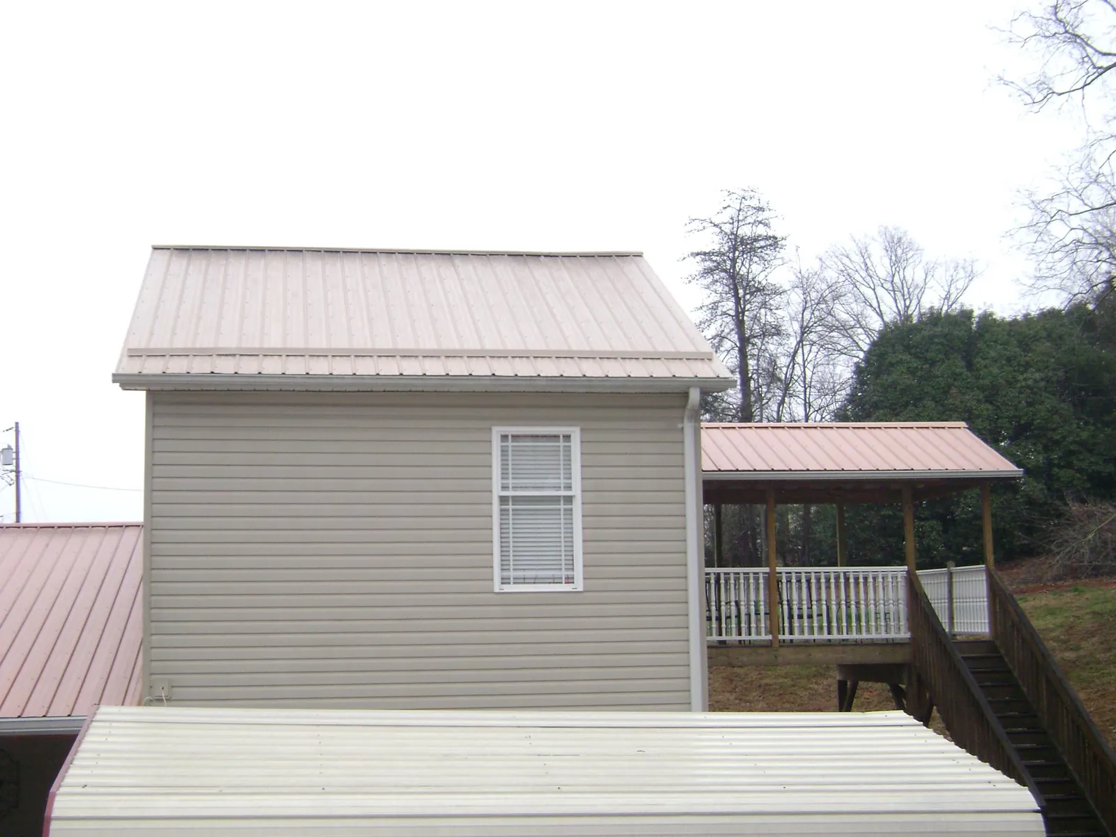 Tan metal roofs on a two story addition and attached porch, from a Roof Replacement job in East Liverpool