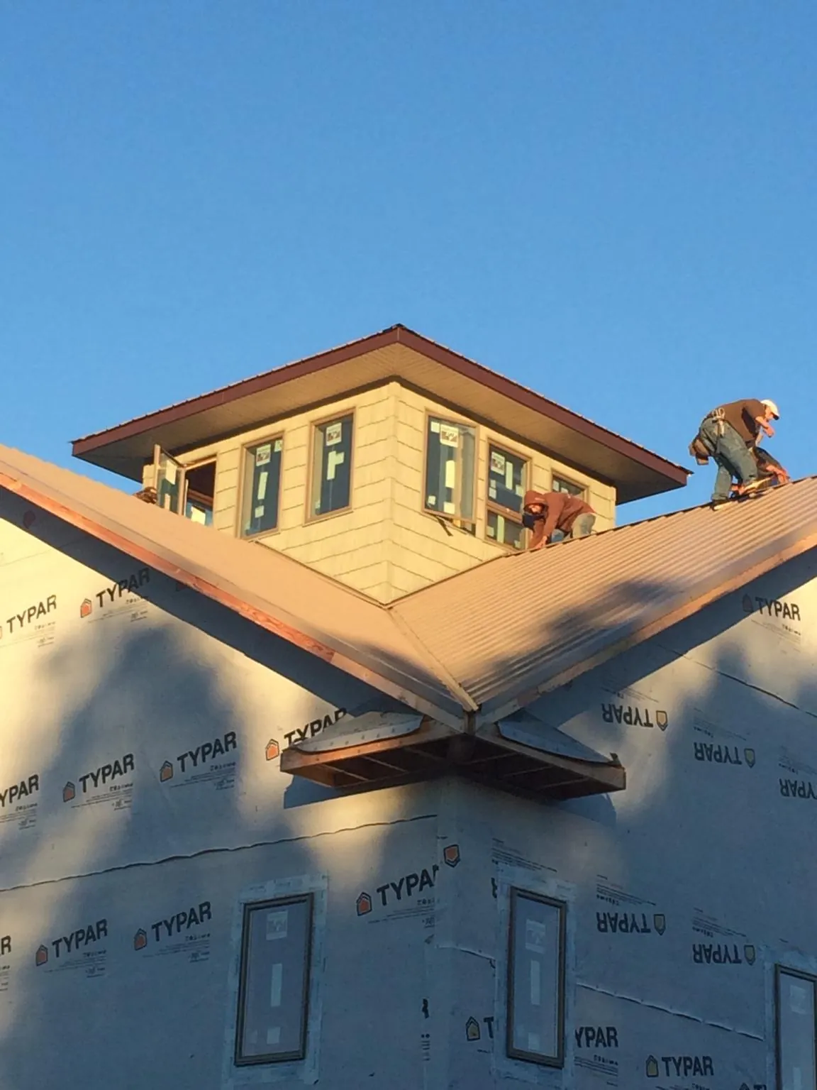 Roofers working around a rooftop cupola on a new metal roof at sunset — Roof Waterproofing in East Liverpool by Roofing Brothers